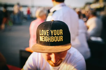 Man wearing a black cap with a love your neighbor print